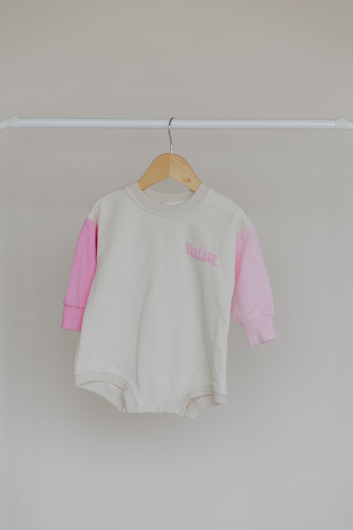 Tiny Threads Co. oversized long sleeve romper in pink in front on view