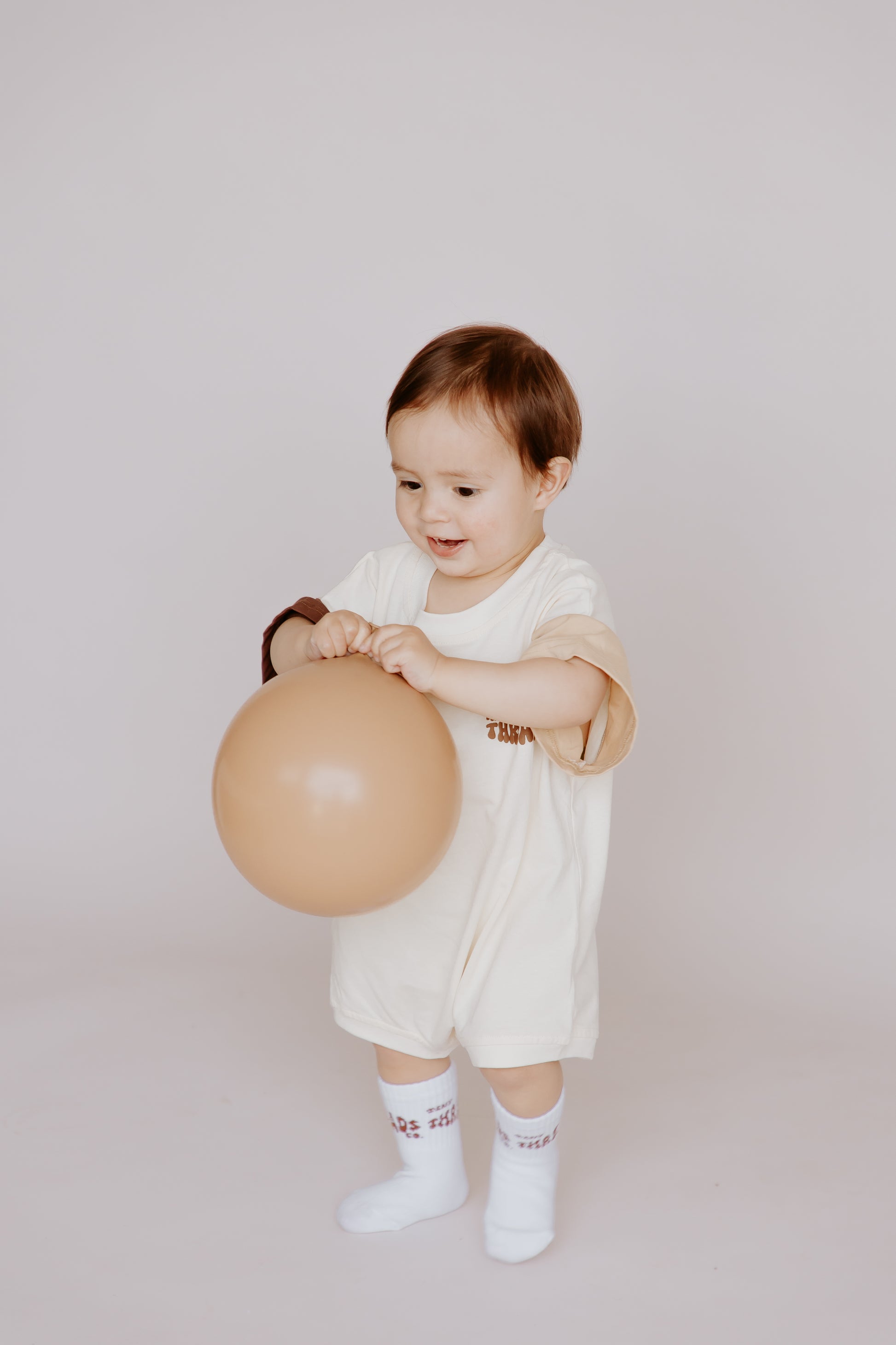 Tiny Threads Co. oversized short sleeve romper in brown, worn by O aged 18 months