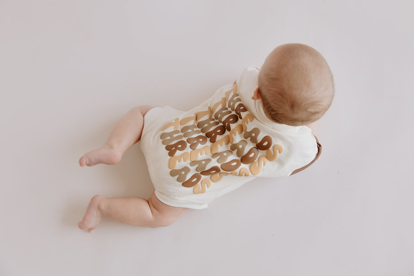 Tiny Threads Co. oversized short sleeve romper in brown, worn by B 5 moths corrected, featuring the back of the romper