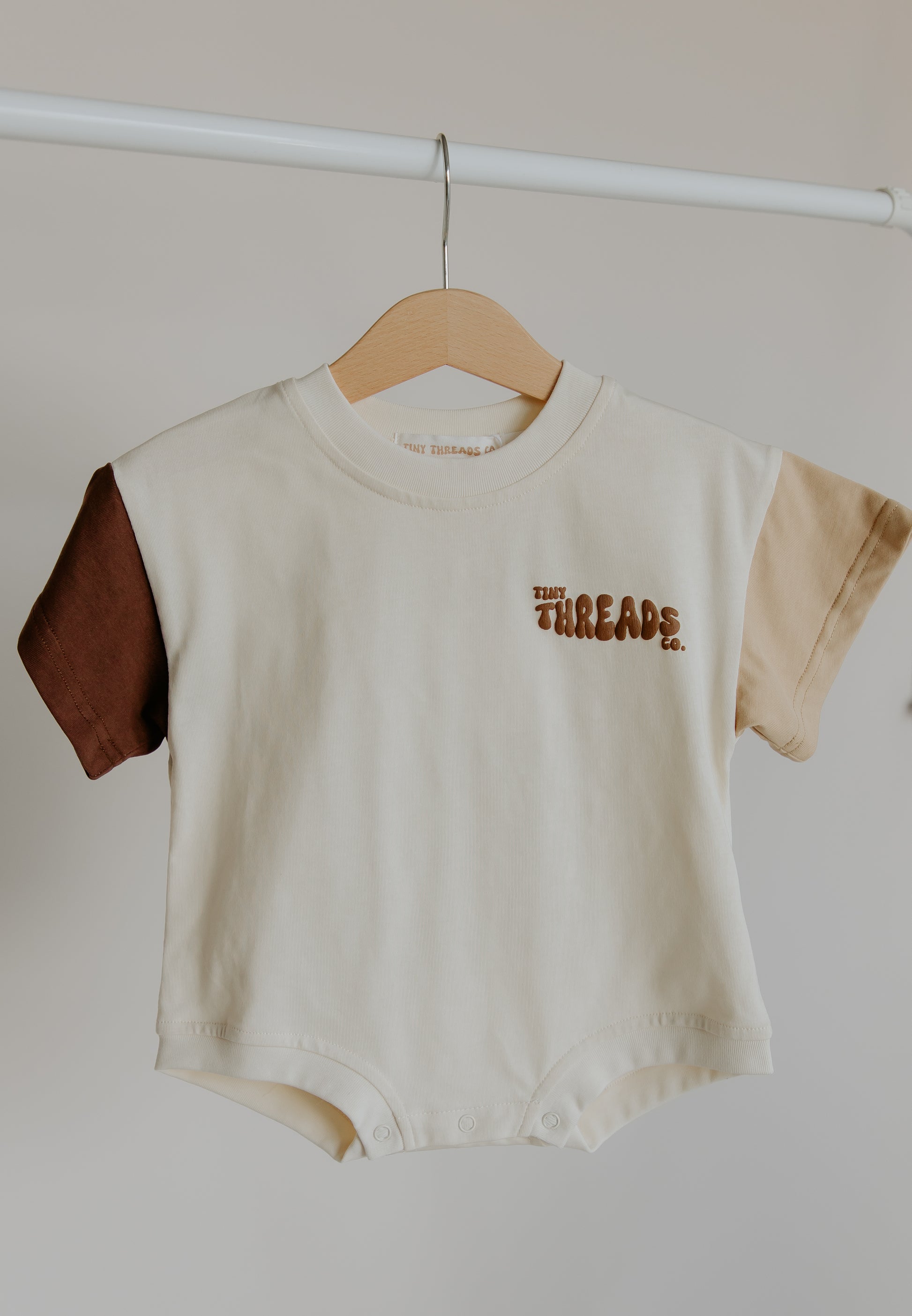 Tiny Threads Co. oversized short sleeve romper in brown, front on view